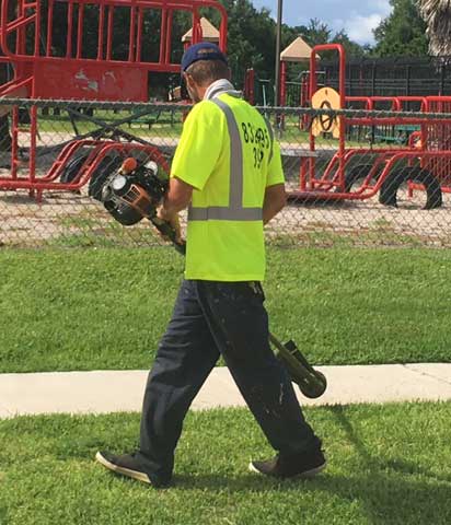 High MTC worker finishing a commercial lawn maintenance job with the trimmer.