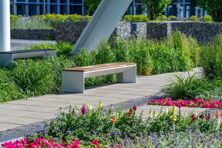 Professional landscaping with a sitting bench at an office building.